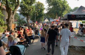 Blick in einen der buntern Straßenzüge mit Tischen und Menschen beim Trinken und Essen in Gesprächen